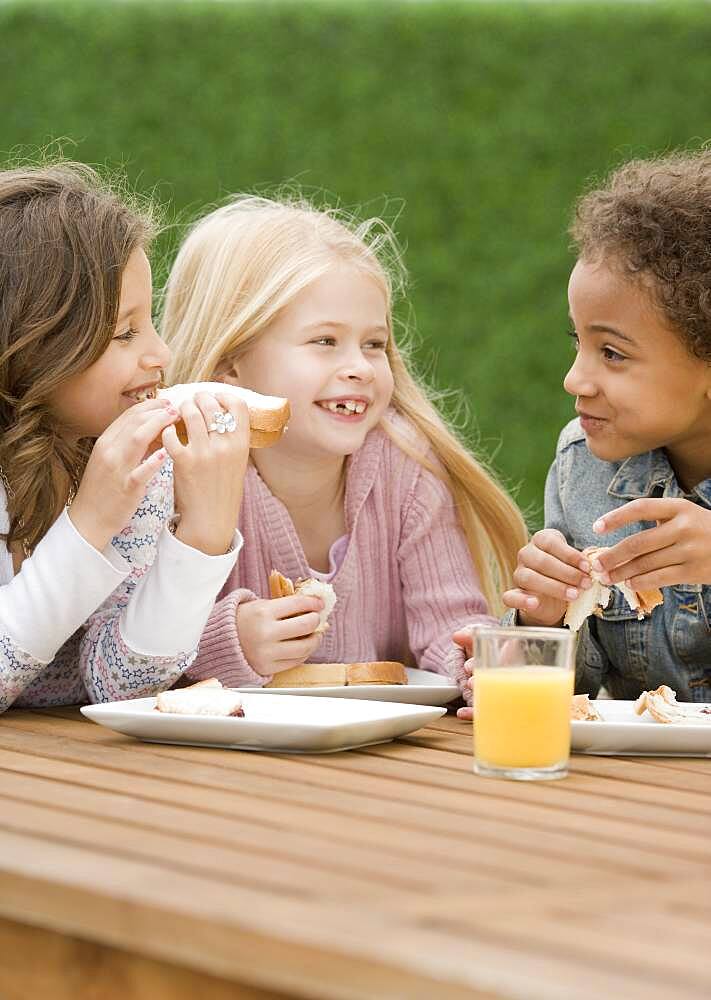 Multi-ethnic girls eating sandwiches