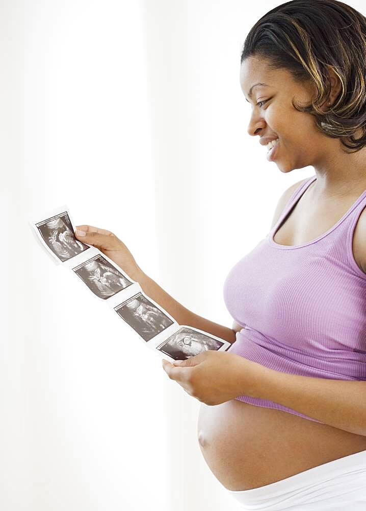 Pregnant African American woman looking at ultrasound printout