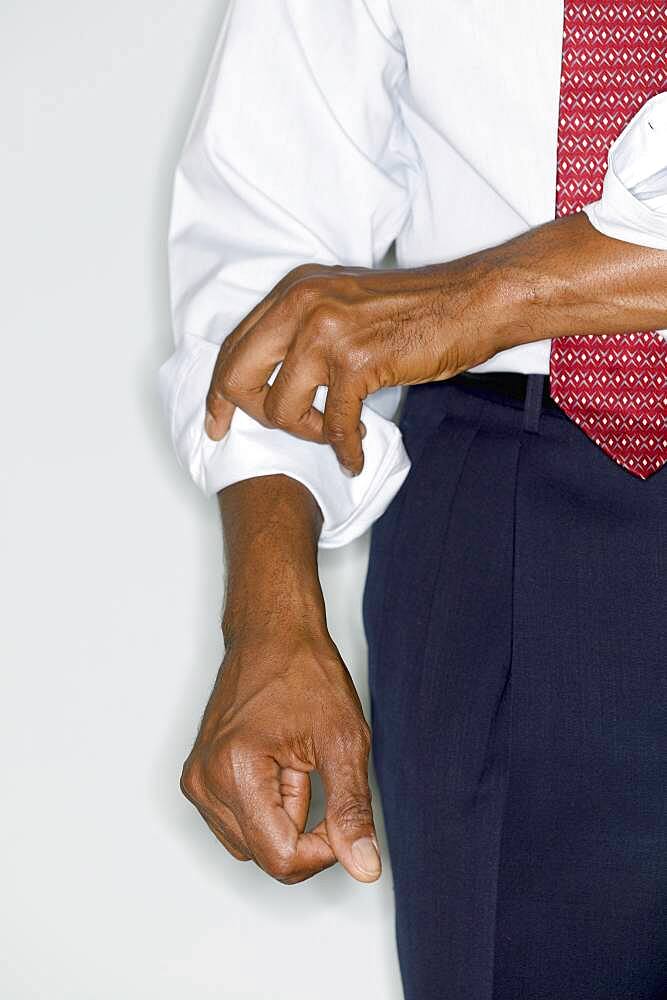 Midsection of businessman rolling up sleeve