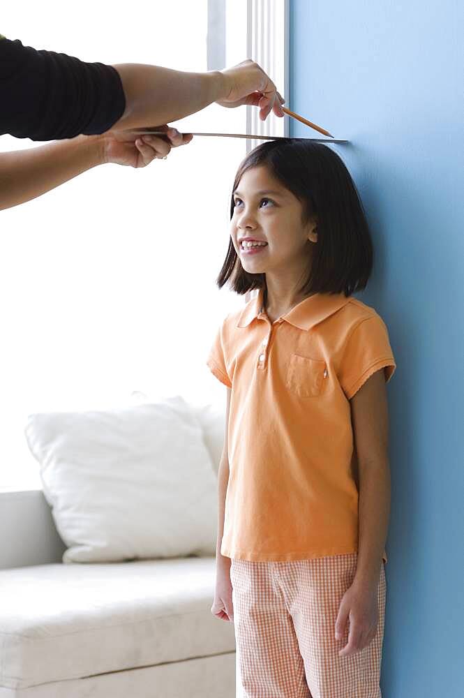 Asian girl having height measured on wall