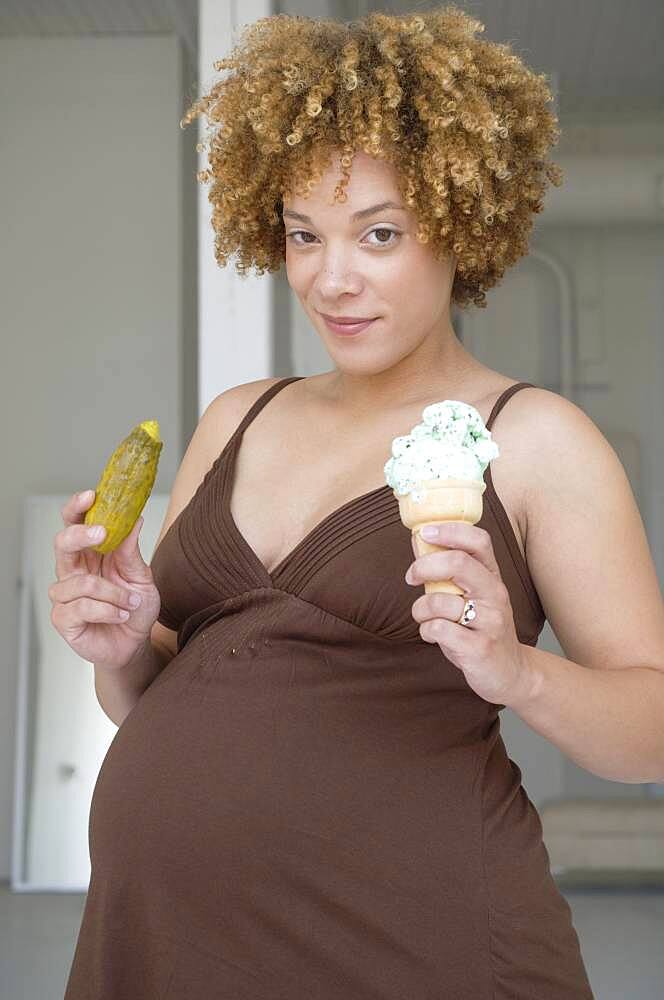 Pregnant African woman holding pickle and ice cream