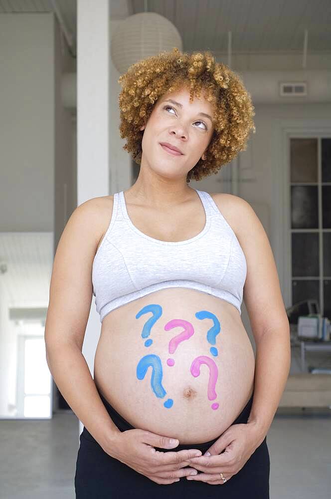 Pregnant African woman with question marks painted on belly