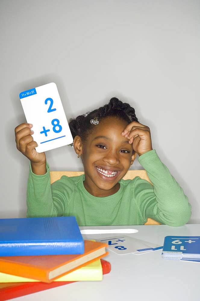 African girl holding addition flash cards