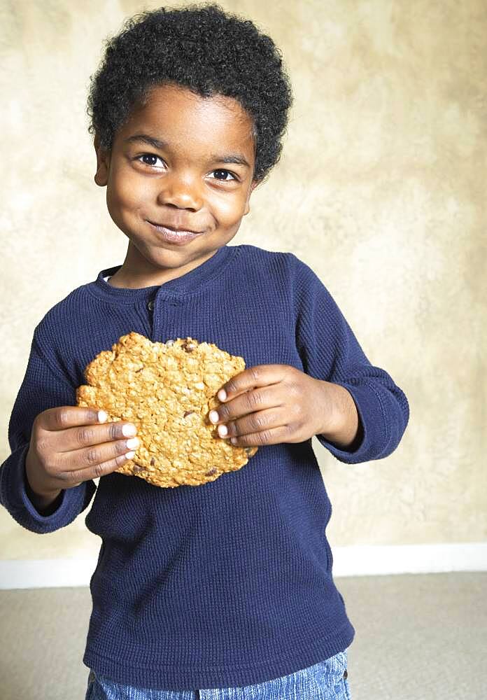 Young African American boy eating large cookie