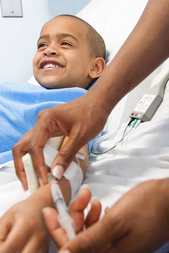 African boy receiving IV medication in hospital bed