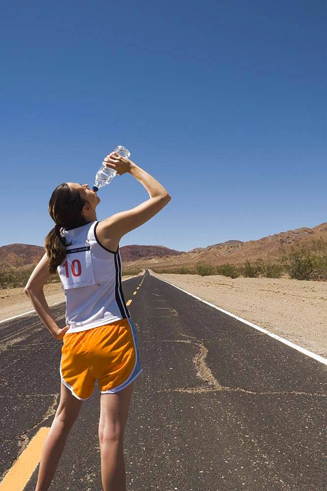 Mixed Race female runner drinking water