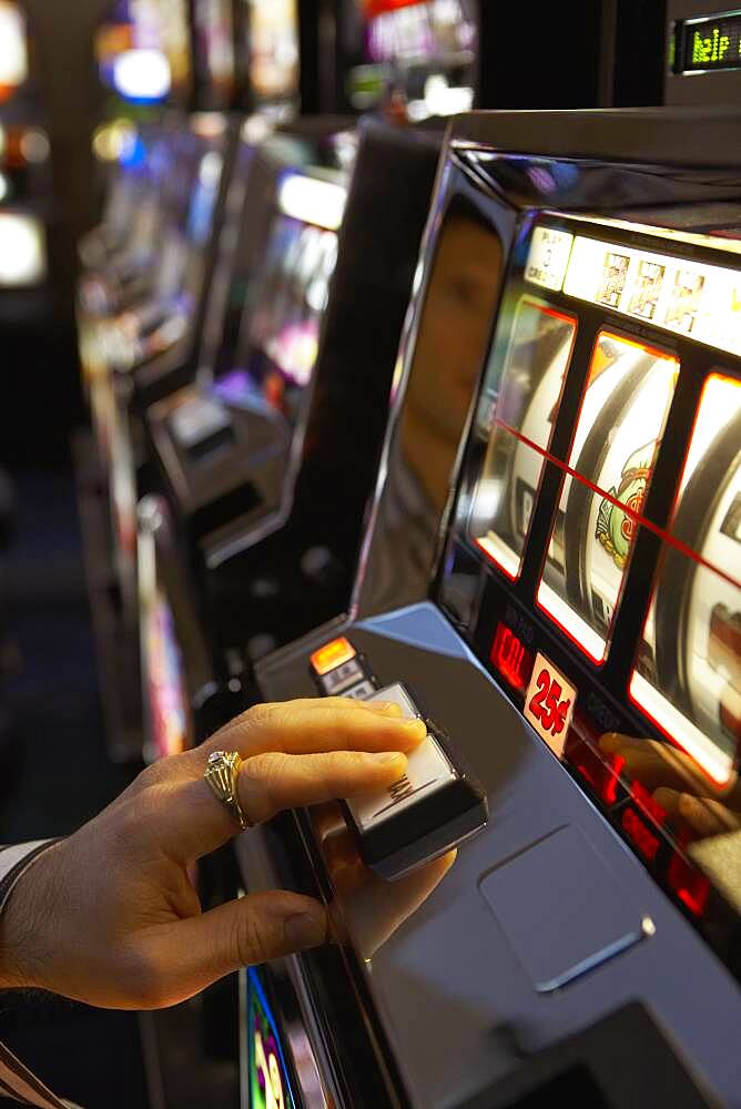 Man pushing the spin button on a slot machine