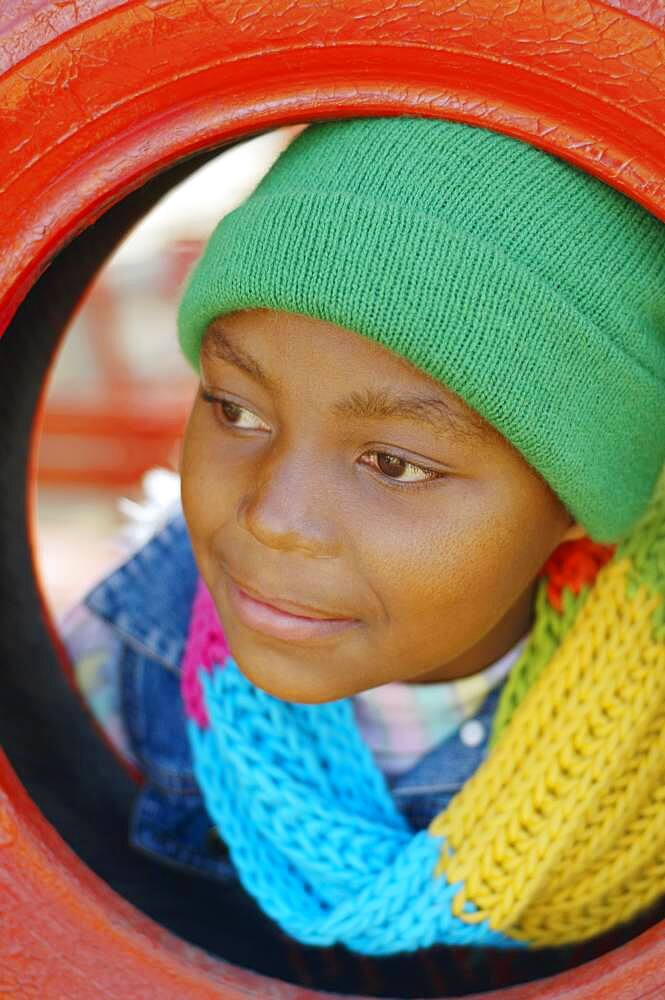 African girl leaning head through tire swing