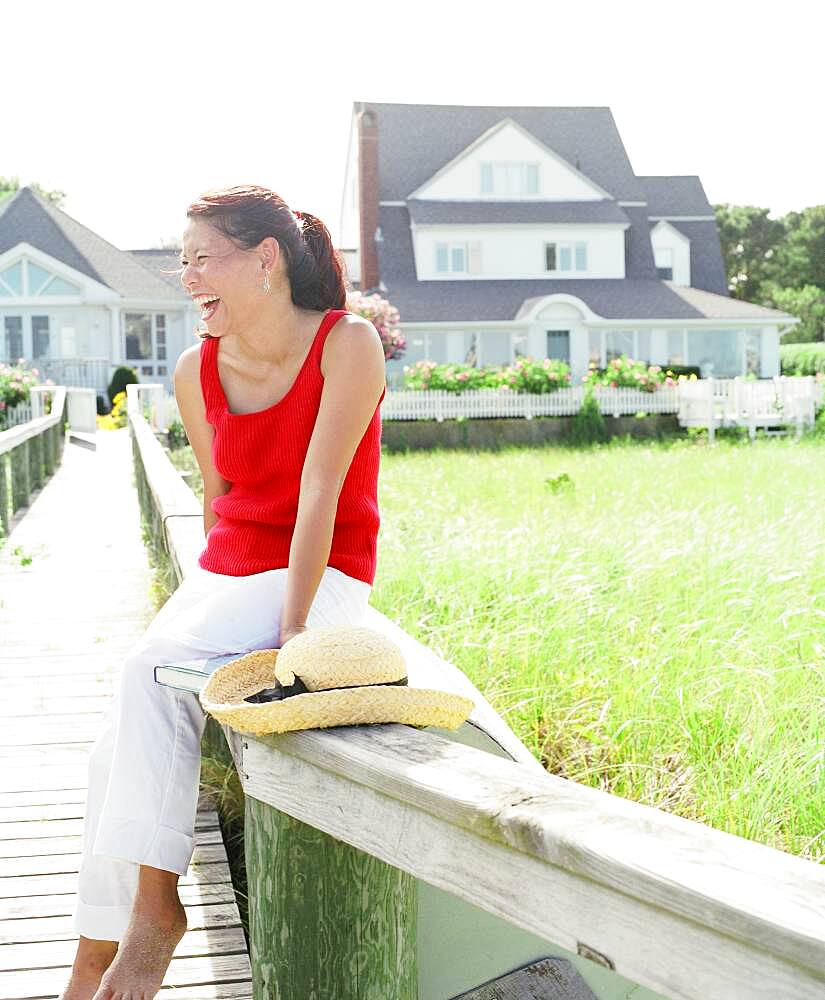 Young woman laughing while sitting on railing