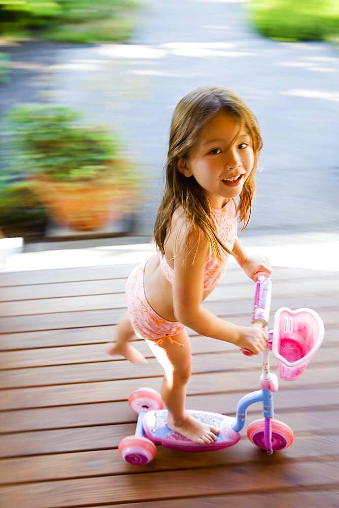 Asian girl riding foot powered scooter