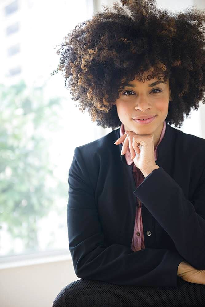 Mixed race businesswoman sitting near window