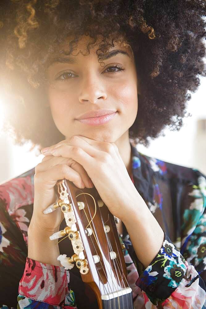 Mixed race musician holding guitar