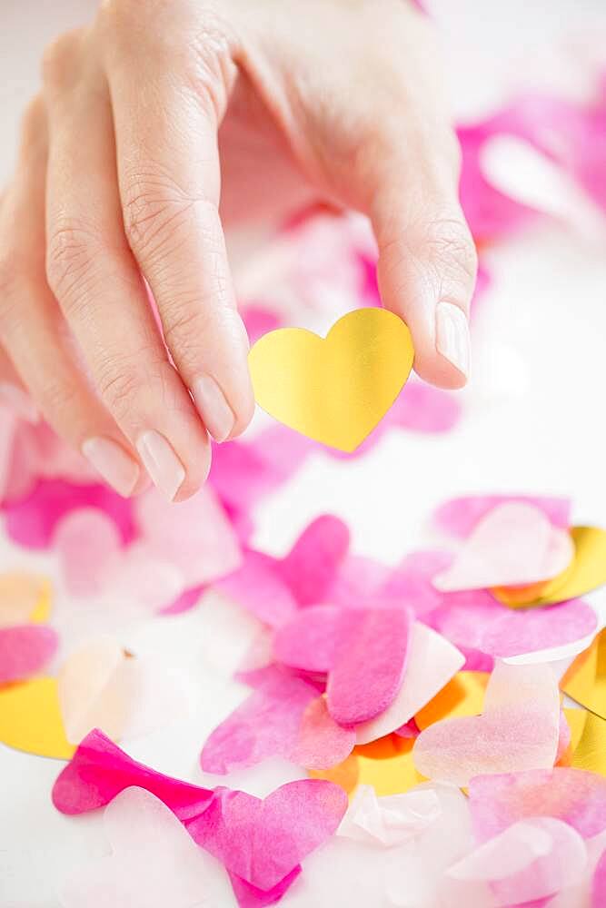 Mixed race woman holding confetti hearts