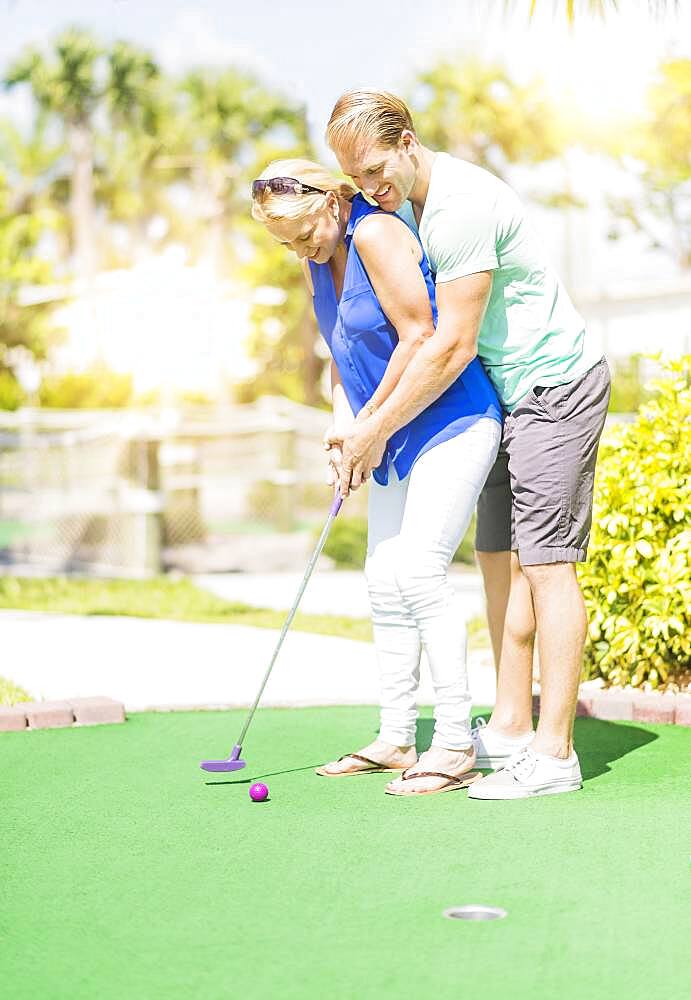 Caucasian couple playing miniature golf