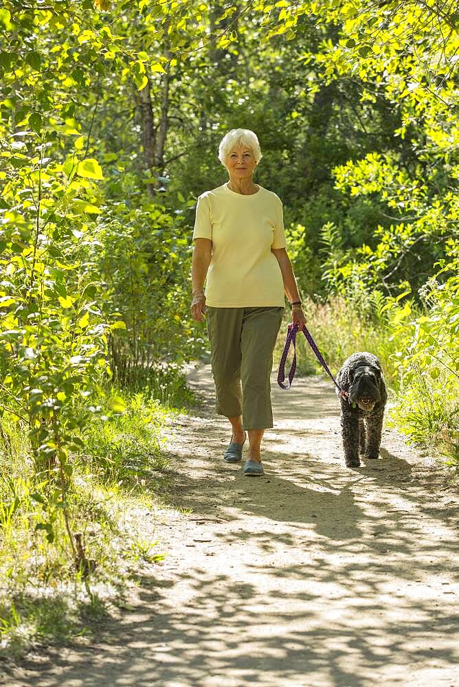 Older Caucasian woman walking dog on dirt path