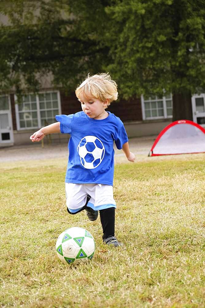 Caucasian boy playing soccer in field