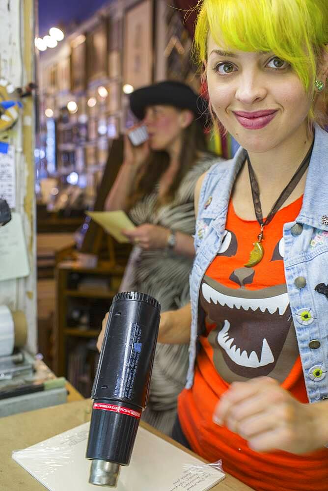 Caucasian artist using heat gun in workshop