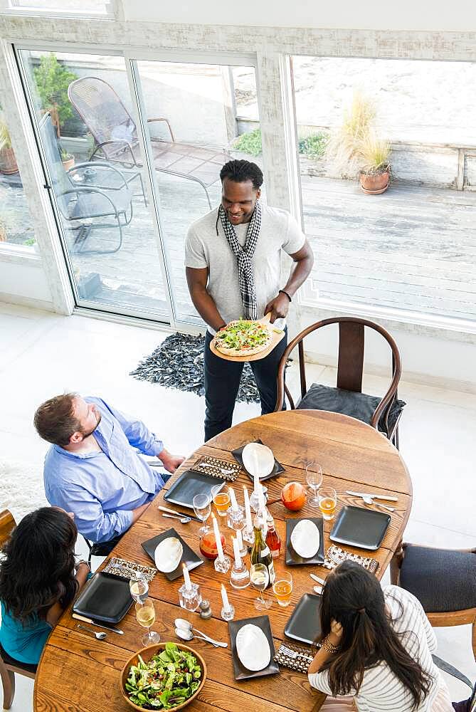 Man serving friends at dinner party