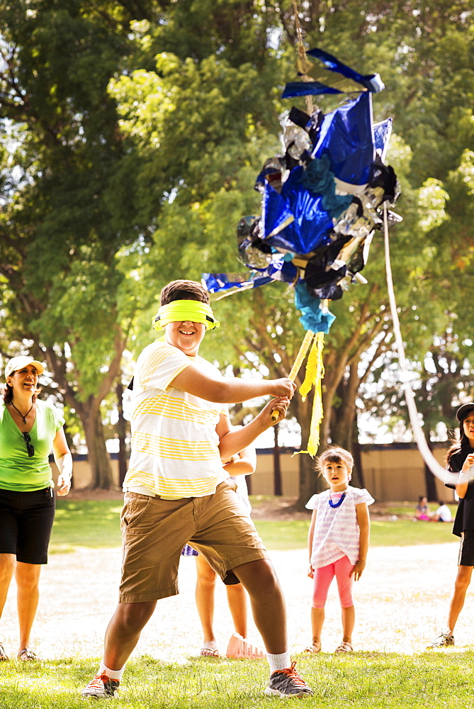 Blindfolded boy hitting pinata at party