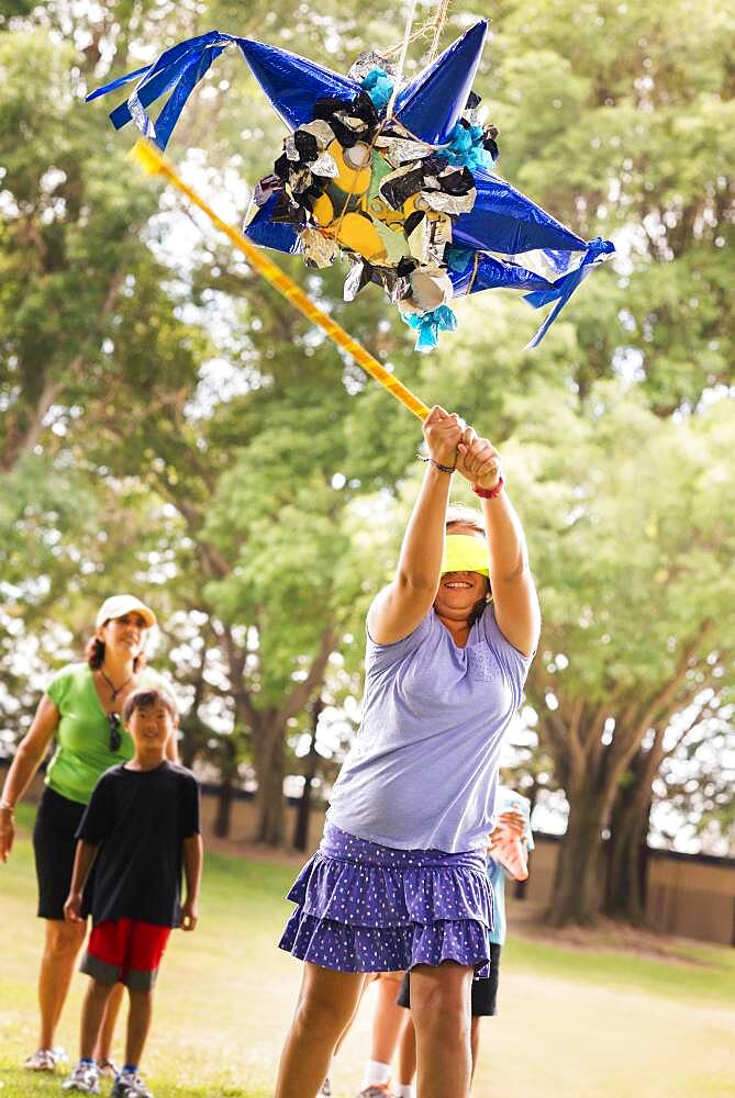 Blindfolded girl hitting pinata at party