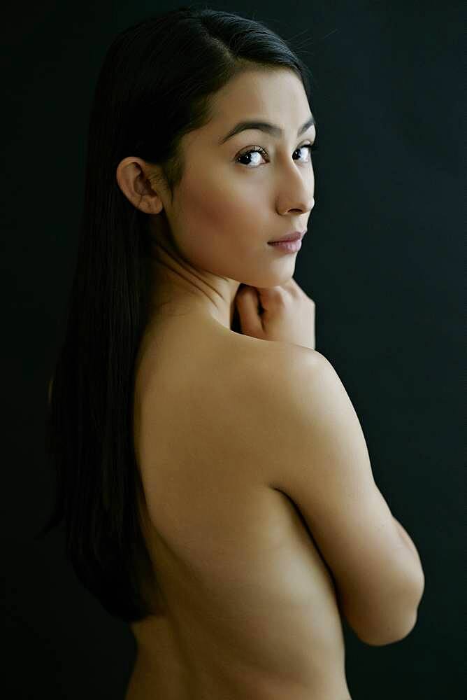 Nude Hispanic woman looking over shoulder