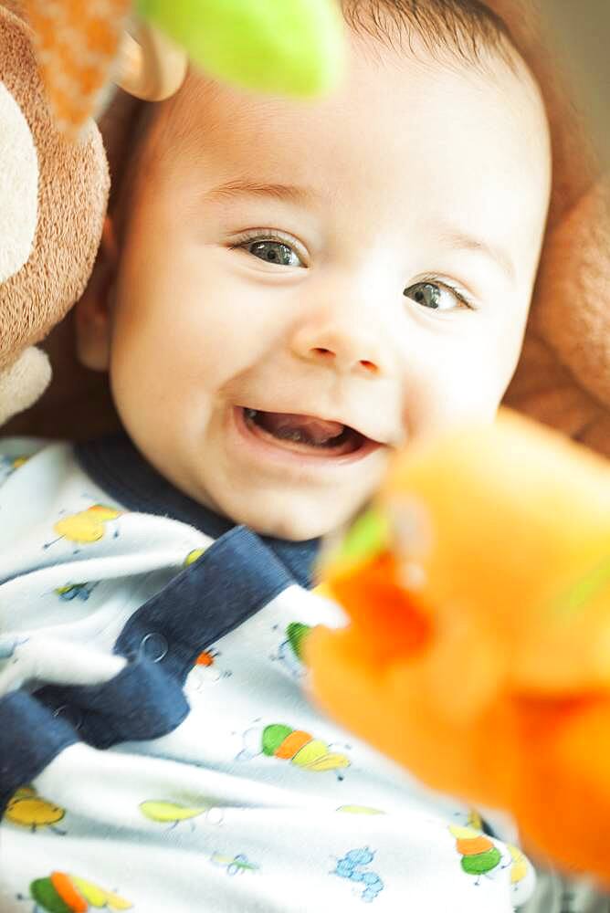 Mixed race baby laying under toys