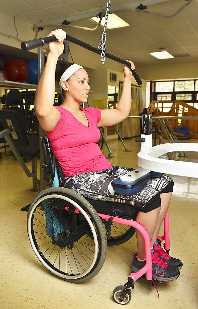 Paraplegic woman in wheelchair working out in physical therapy