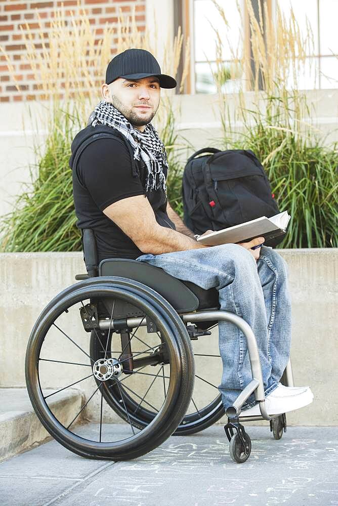 Disabled student in wheelchair reading book