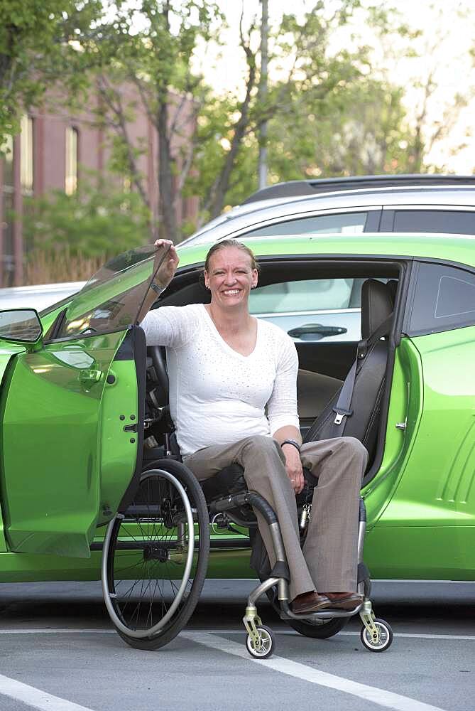 Disabled woman in wheelchair climbing into car