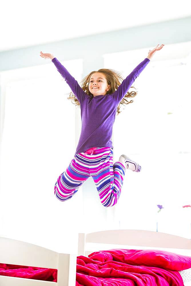 Caucasian girl jumping on bed