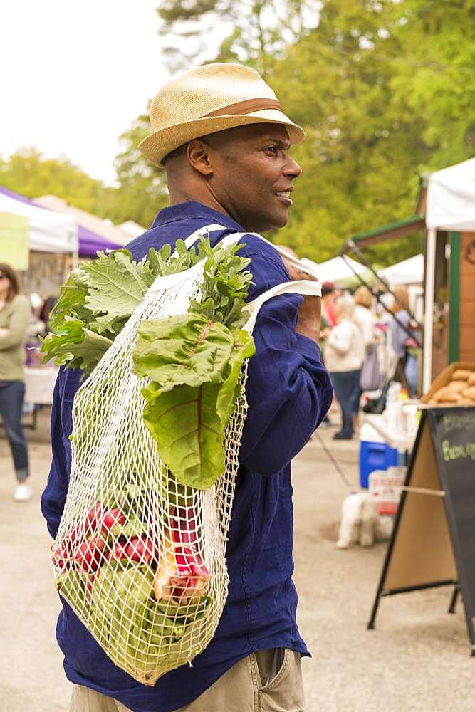 African American man carrying bag of produce at market