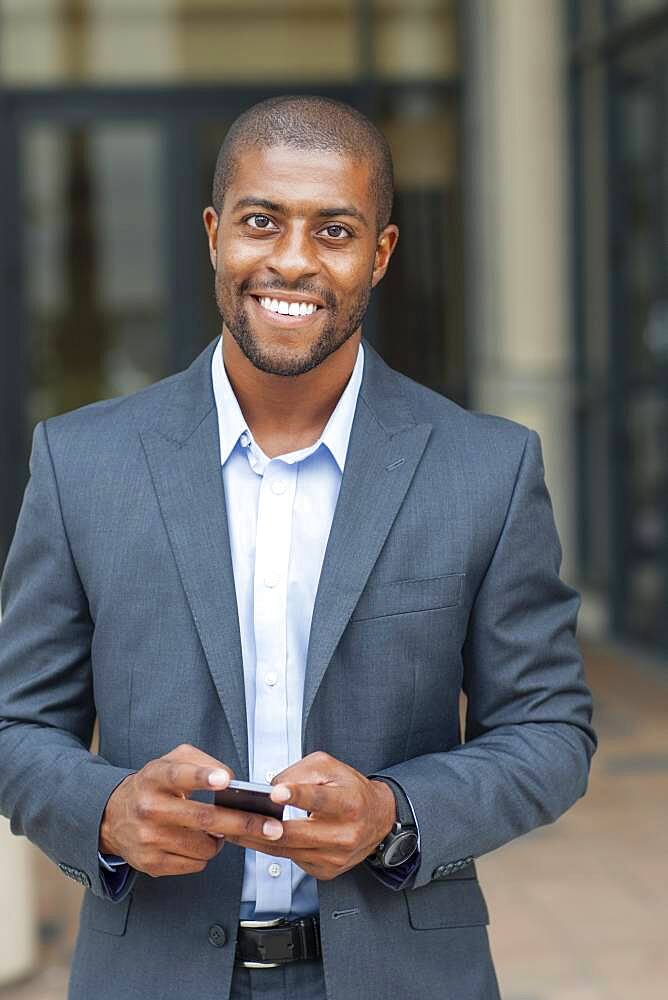 Black businessman using cell phone in city