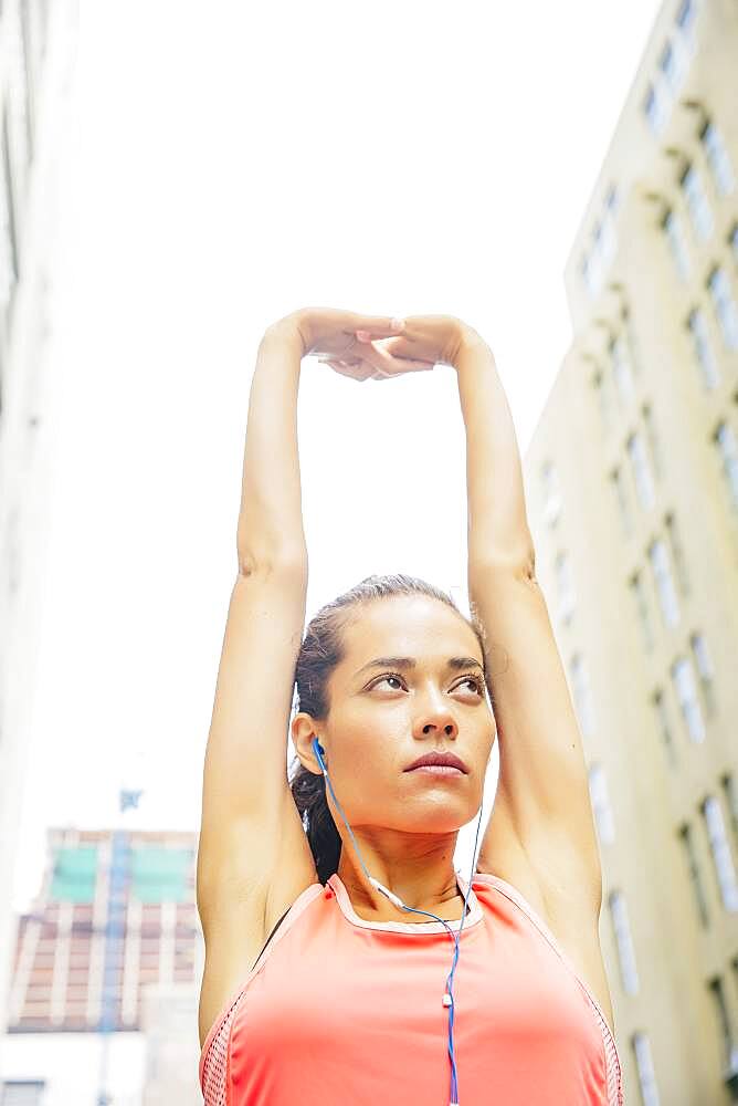 Mixed race athlete stretching in city