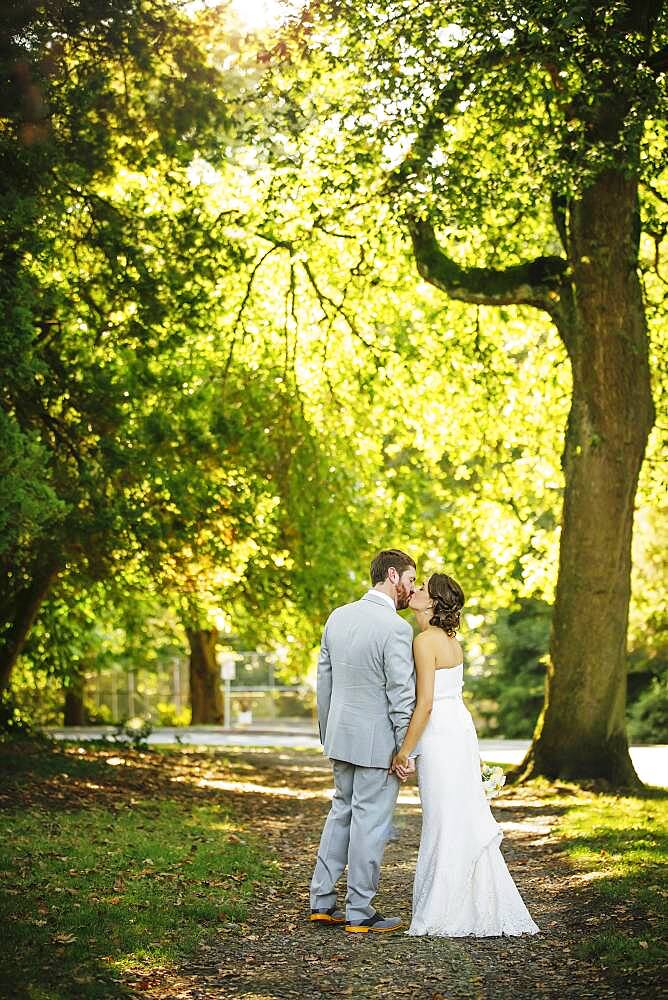 Caucasian bride and groom kissing on dirt path