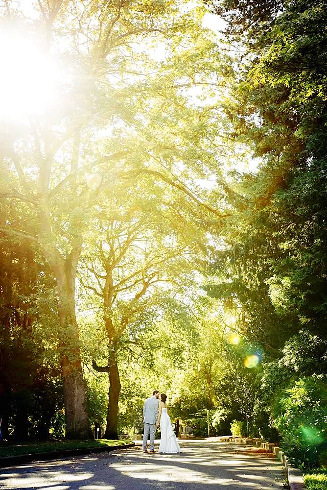 Caucasian bride and groom kissing on rural road