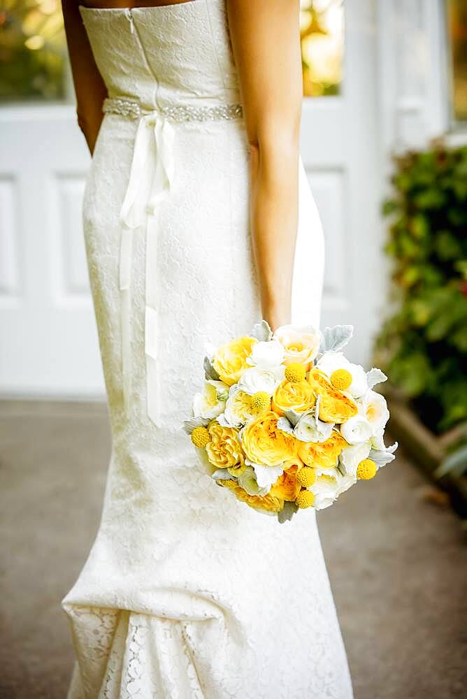 Caucasian bride holding bouquet in garden