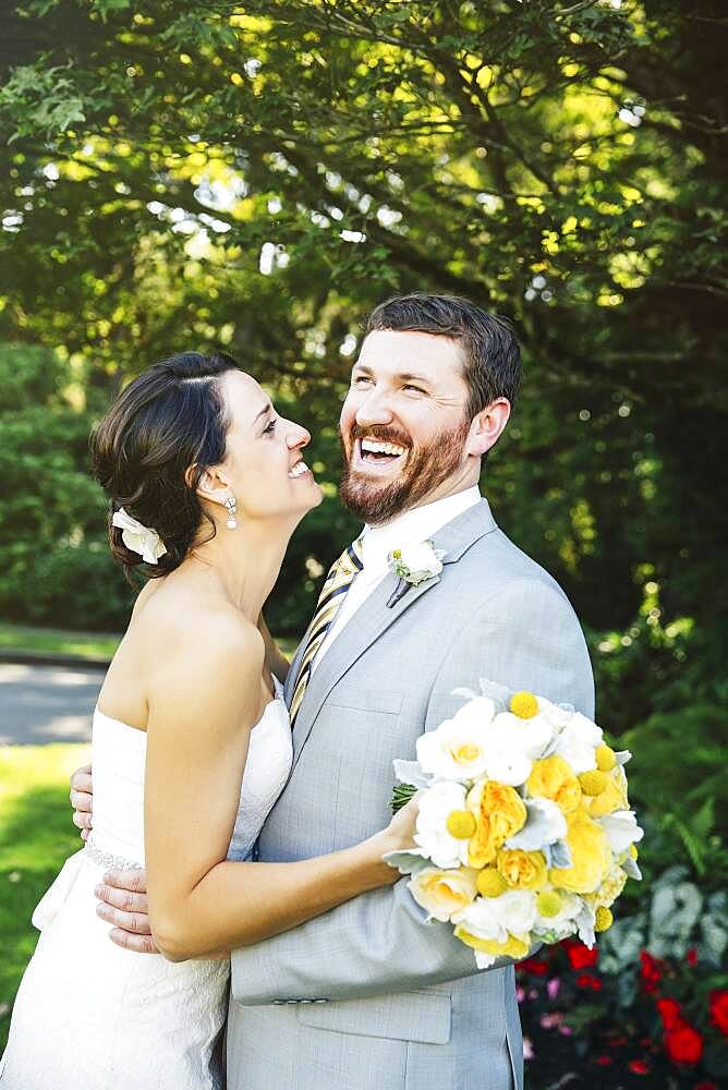 Caucasian bride and groom hugging in garden