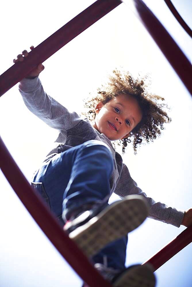 Low angle view of mixed race boy climbing on play structure