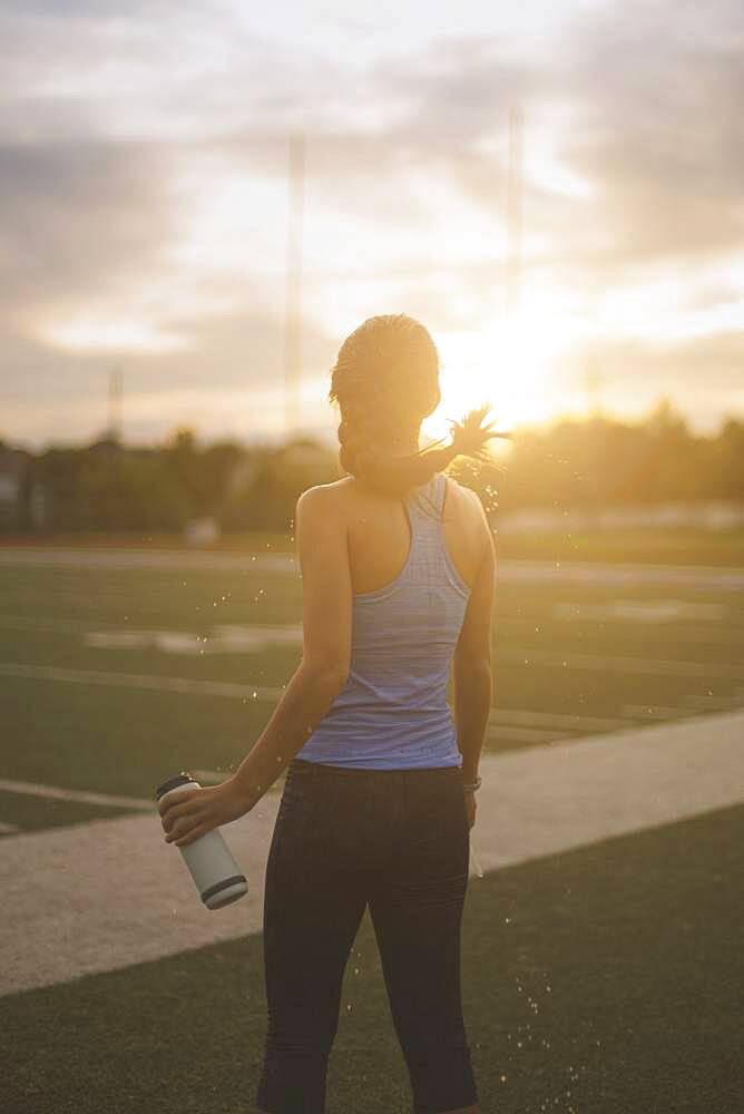 Mixed race athlete holding water bottle on sports field