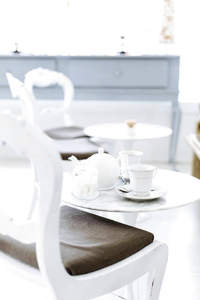 Cafe table with cups of coffee and coffee pot