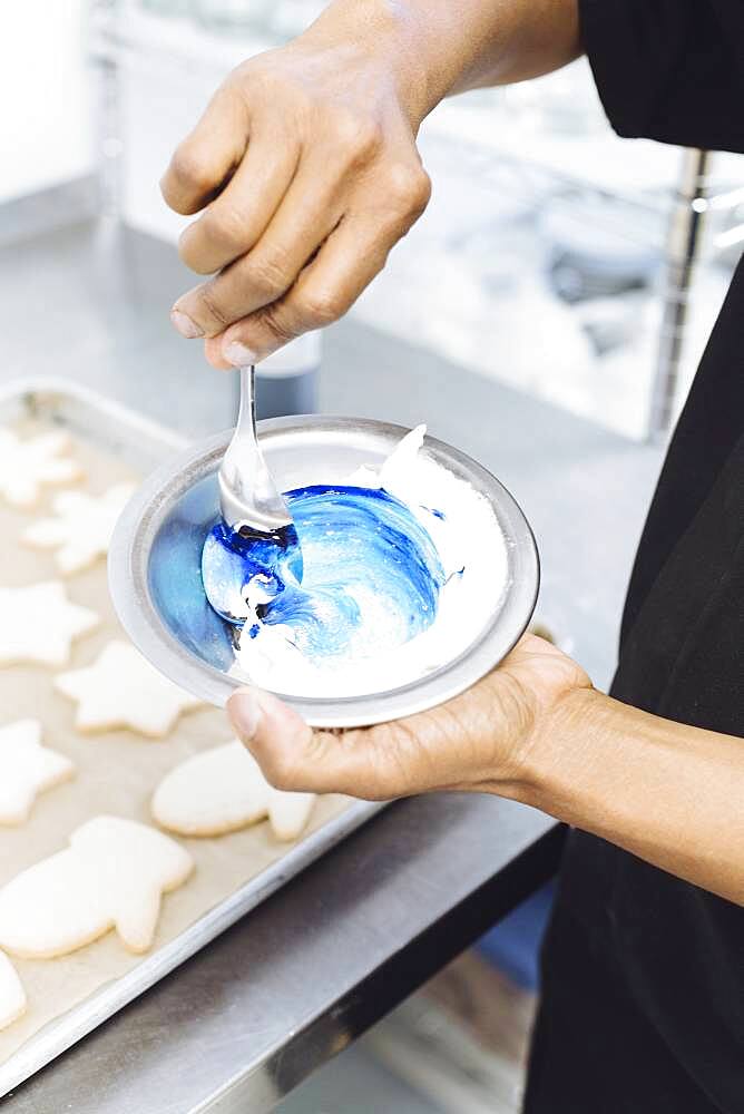 Close up of baker making blue frosting in bakery