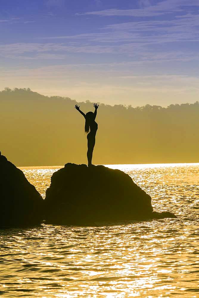 Mixed race woman standing on rock over ocean