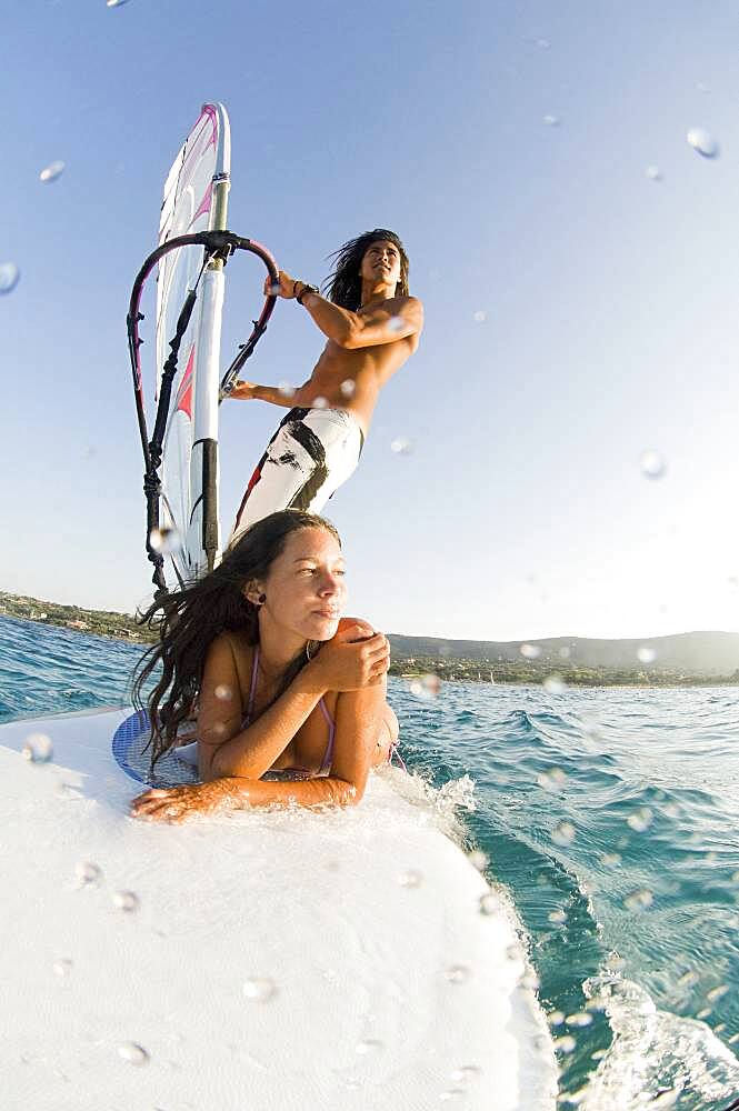 Low angle view of couple windsurfing on ocean