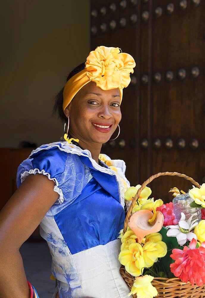 Hispanic woman carrying basket of flowers