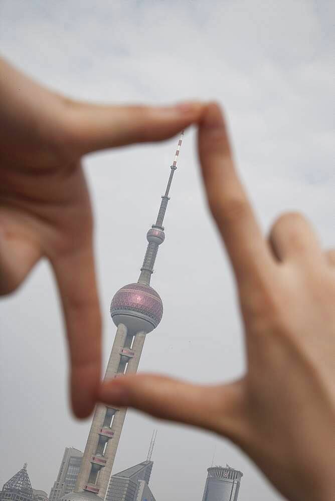 Chinese woman framing Shanghai tower, Shanghai, China