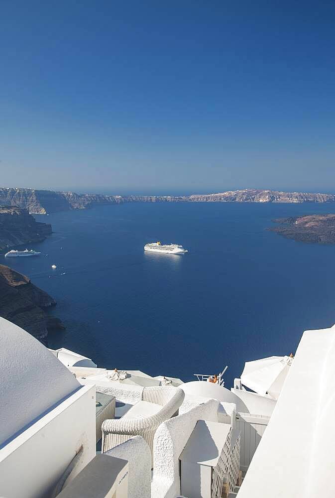 Hillside buildings over cruise ship in Santorini bay, Cyclades, Greece