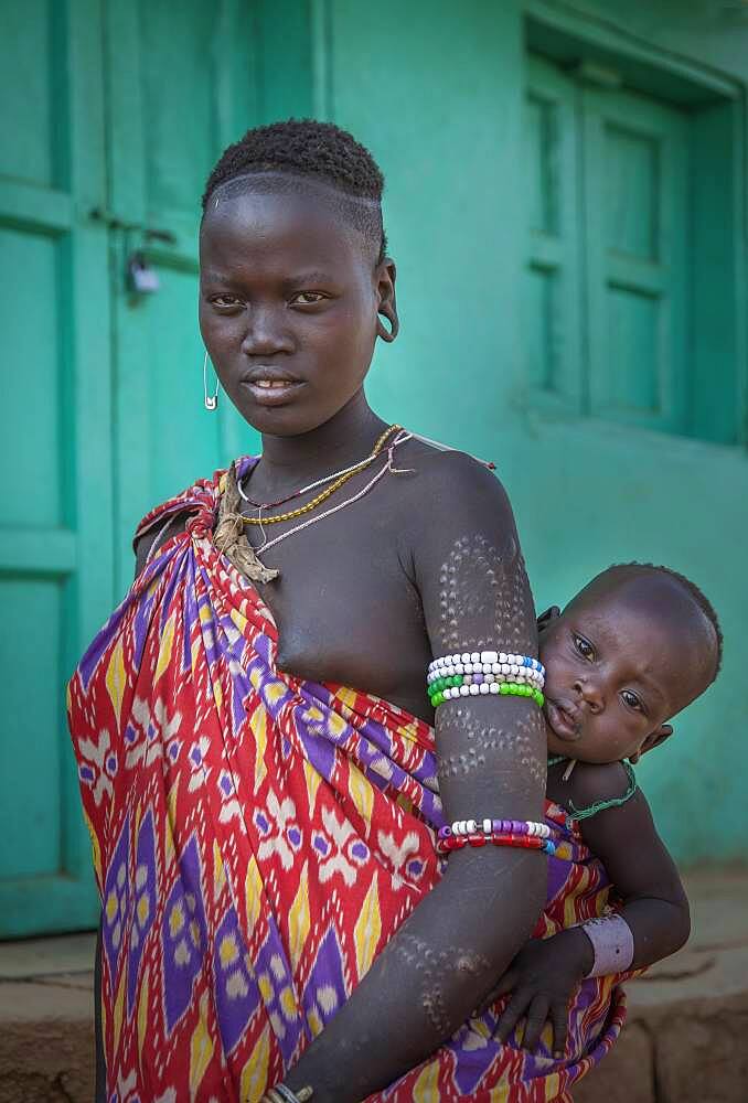 Black woman carrying daughter in sling