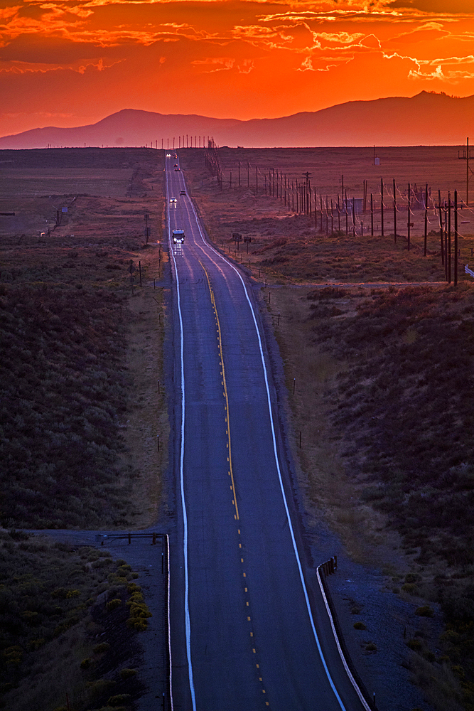 Cars driving on remote road at sunset