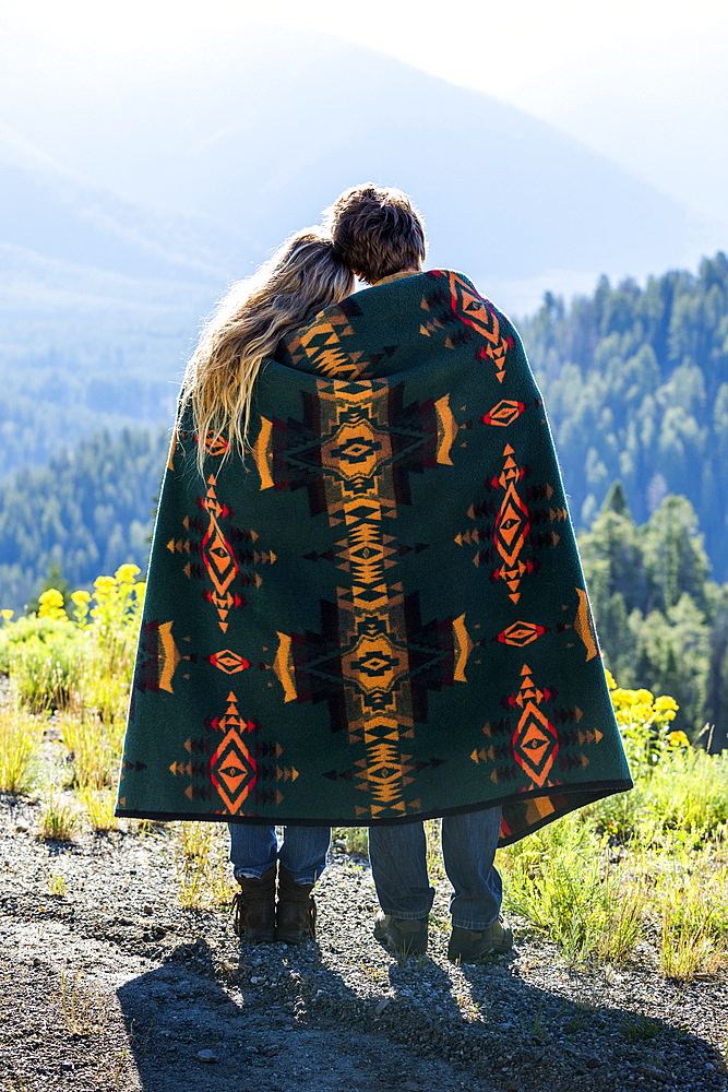 Caucasian couple wrapped in blanket admiring scenic view of landscape