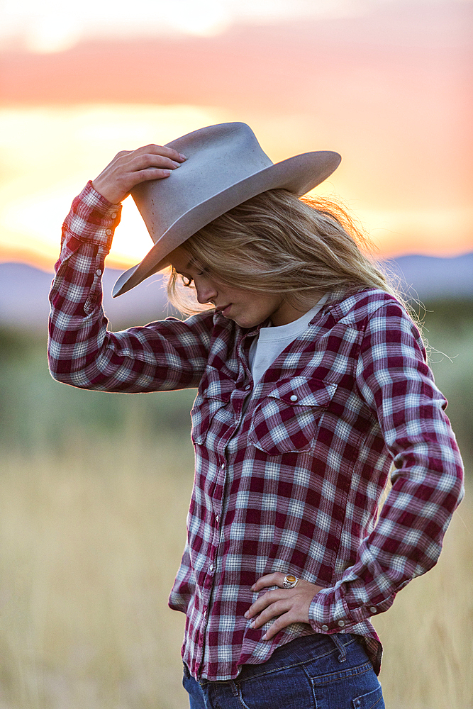 Caucasian teenage girl wearing cowboy hat at sunset